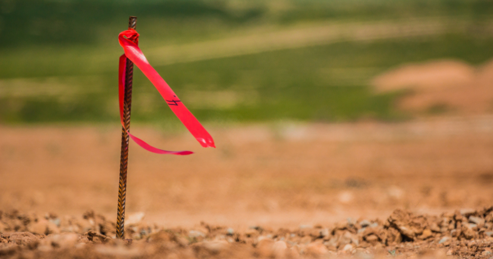 A property stake in the ground with red flag tape.