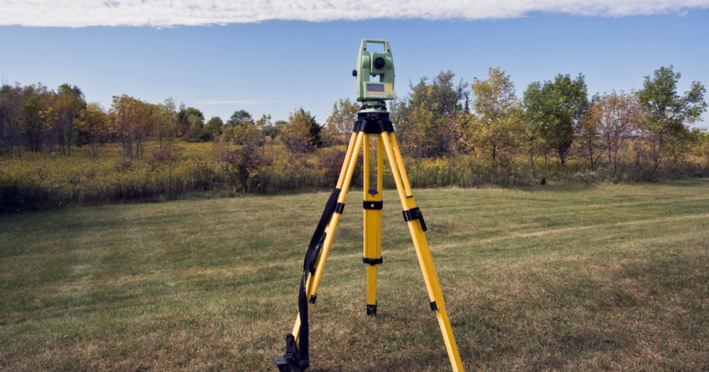 A total station standing in a field. A total station standing in a field.