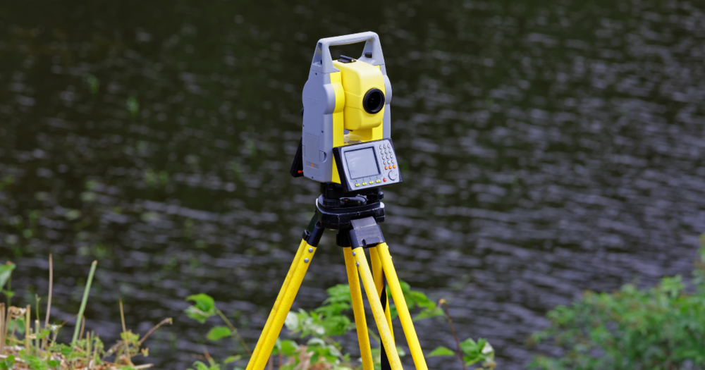 A robotic total station next to a river.