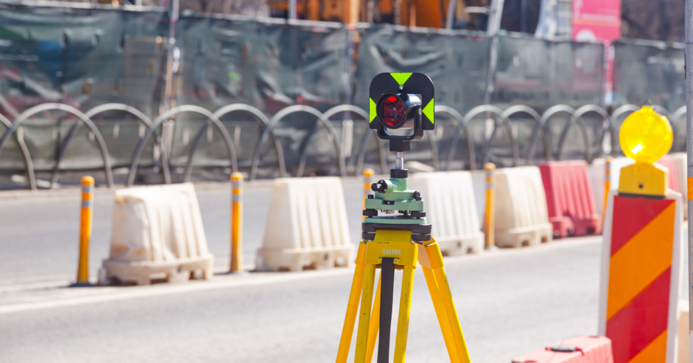 A prism target for a total station on a tripod on a road.