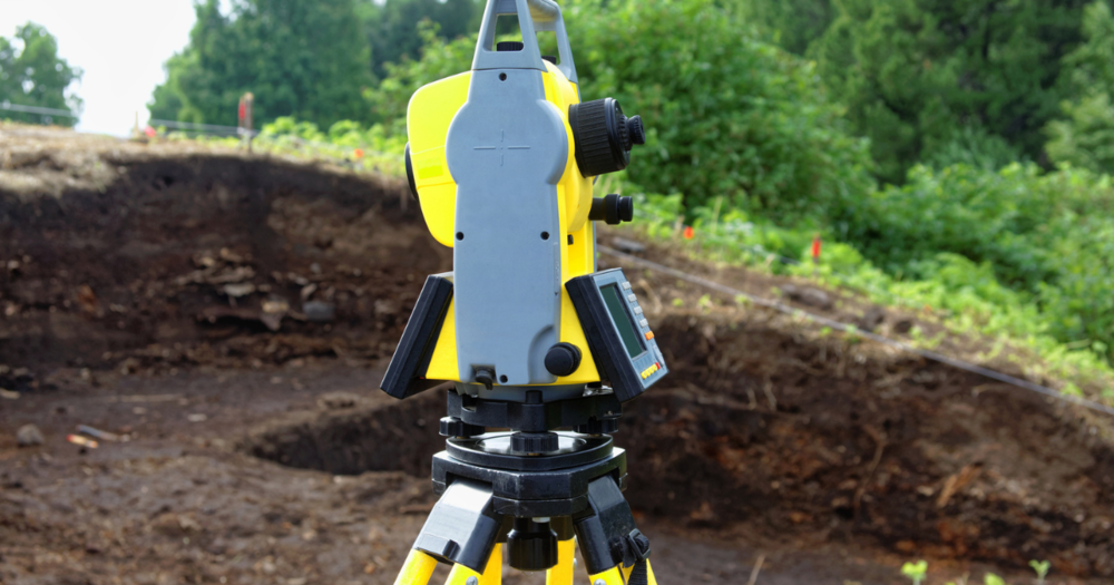 A total station being used in a mud field.